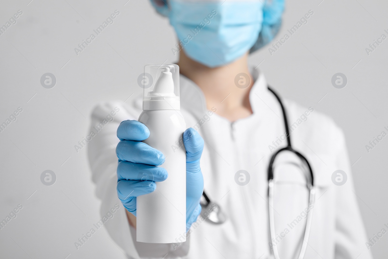 Photo of Doctor holding nasal spray on white background, closeup