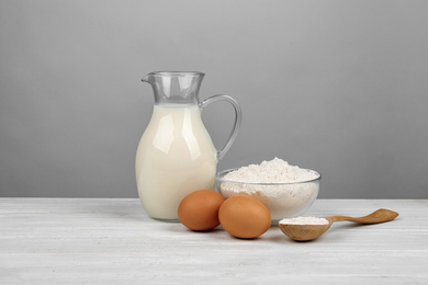 Photo of Raw eggs and other ingredients on white wooden table. Baking pie