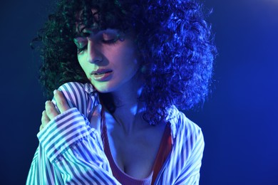 Beautiful young woman posing on color background in neon lights, closeup