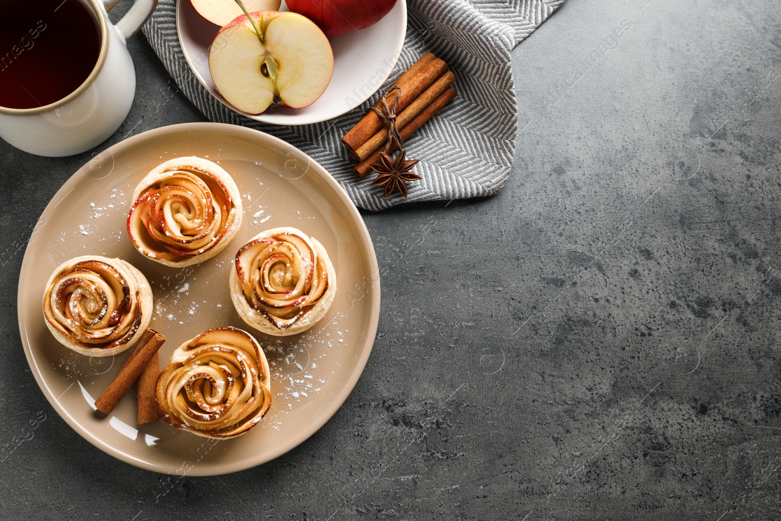 Photo of Freshly baked apple roses served on grey table, flat lay. Space for text