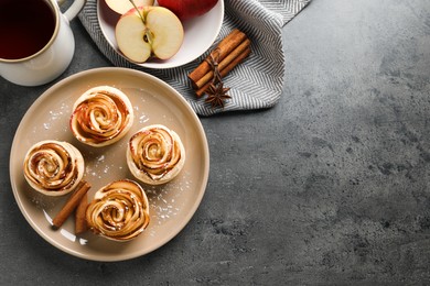 Photo of Freshly baked apple roses served on grey table, flat lay. Space for text