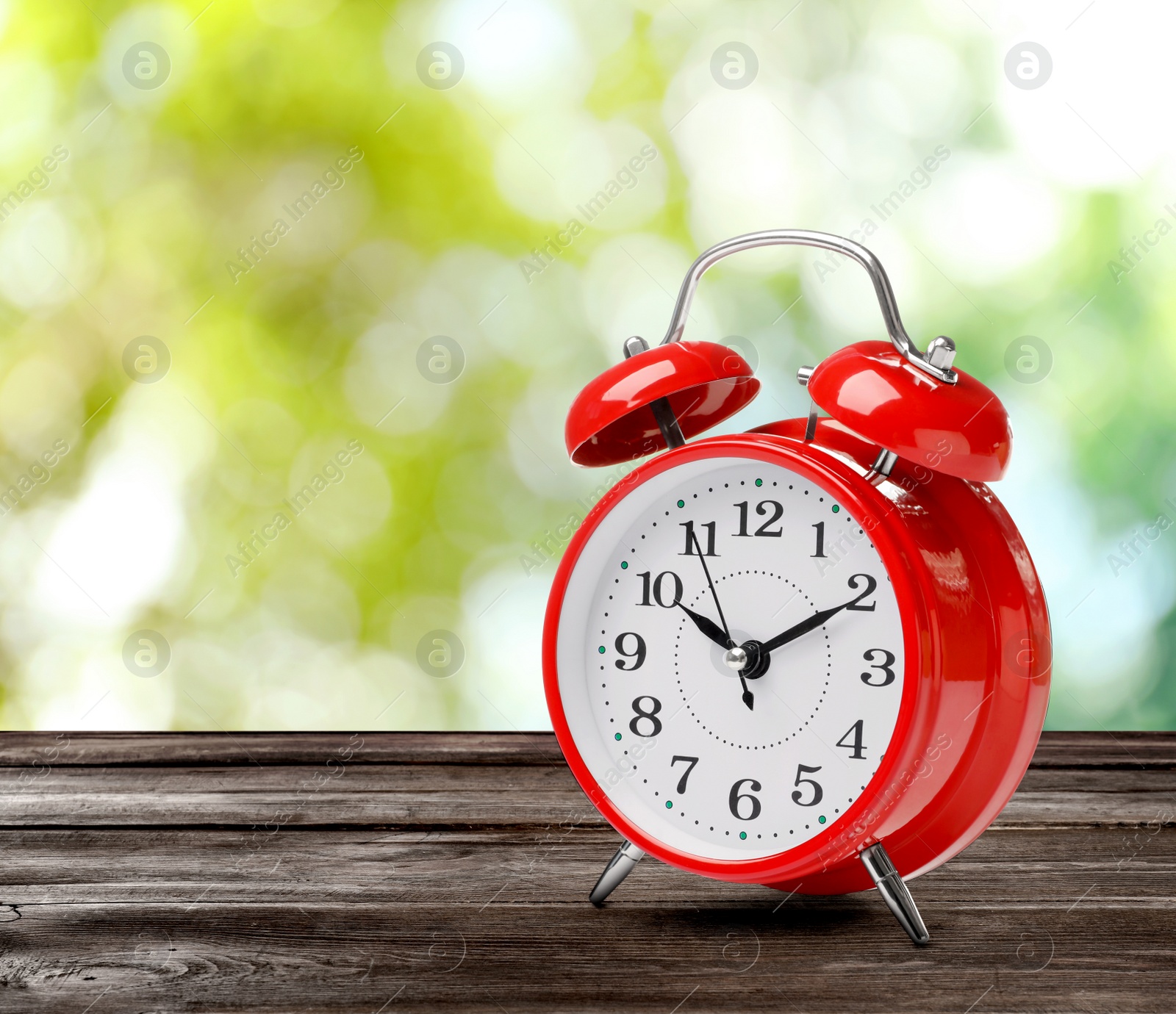 Image of Red alarm clock on wooden table, space for text. Daylight saving time (Spring forward)