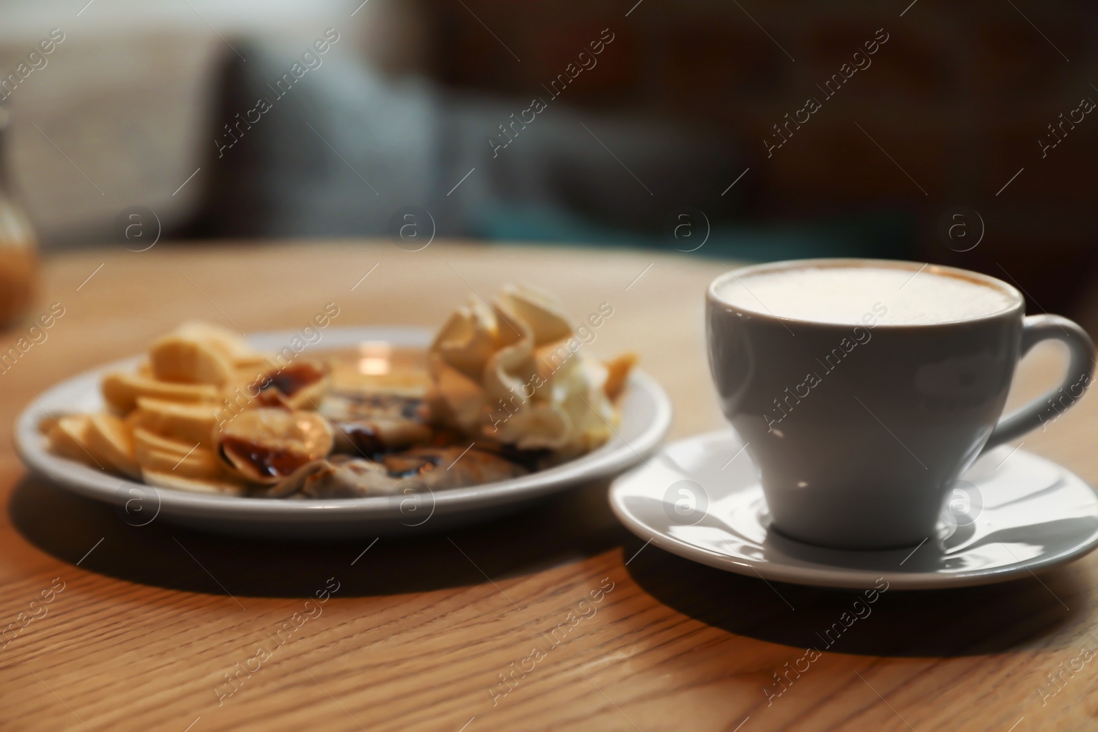 Photo of Cup of aromatic coffee and delicious desserts on wooden table indoors