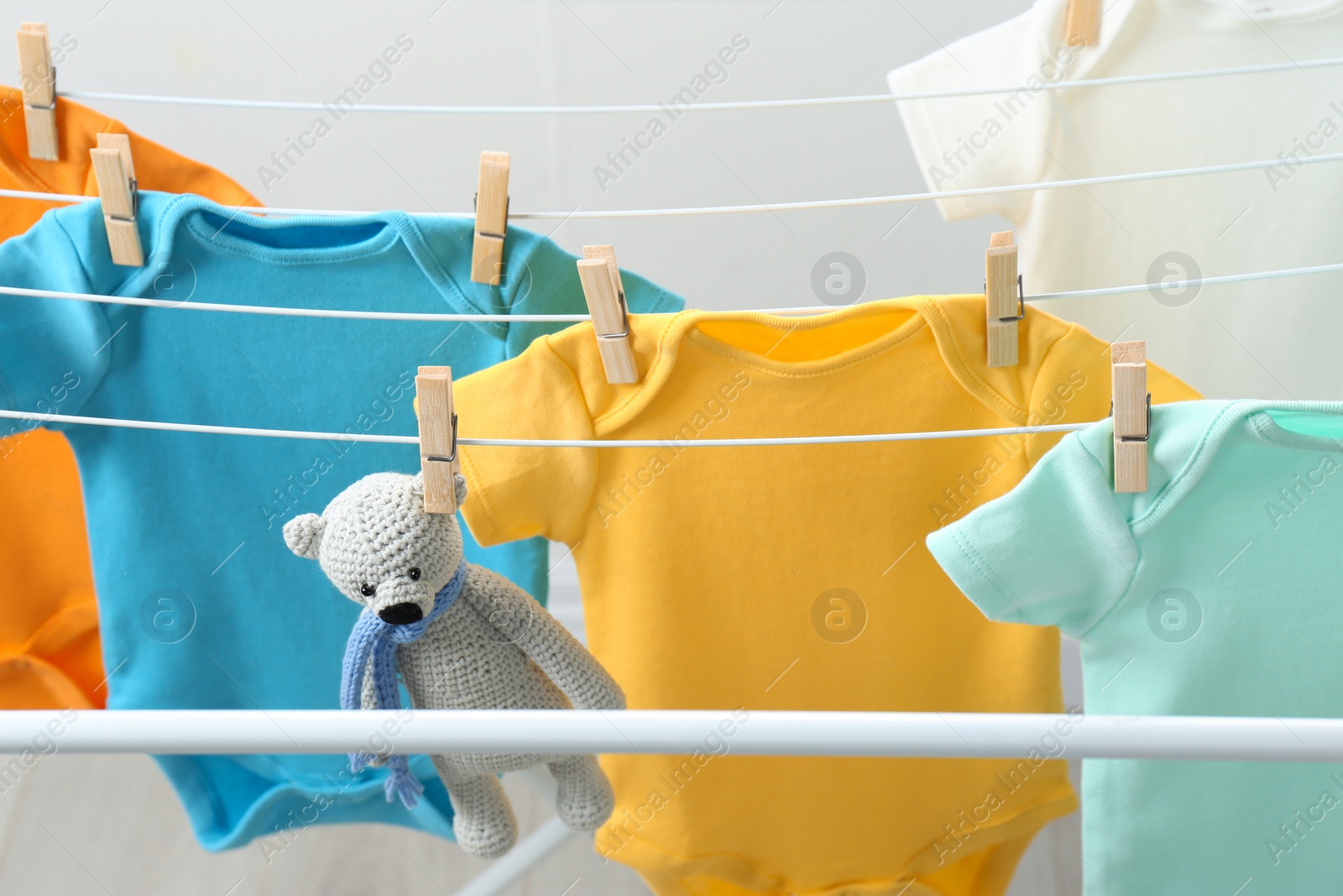 Photo of Different cute baby onesies and toy bear hanging on clothes line. Laundry day