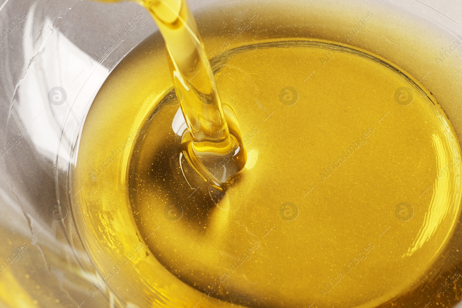 Photo of Pouring cooking oil into bowl, closeup view