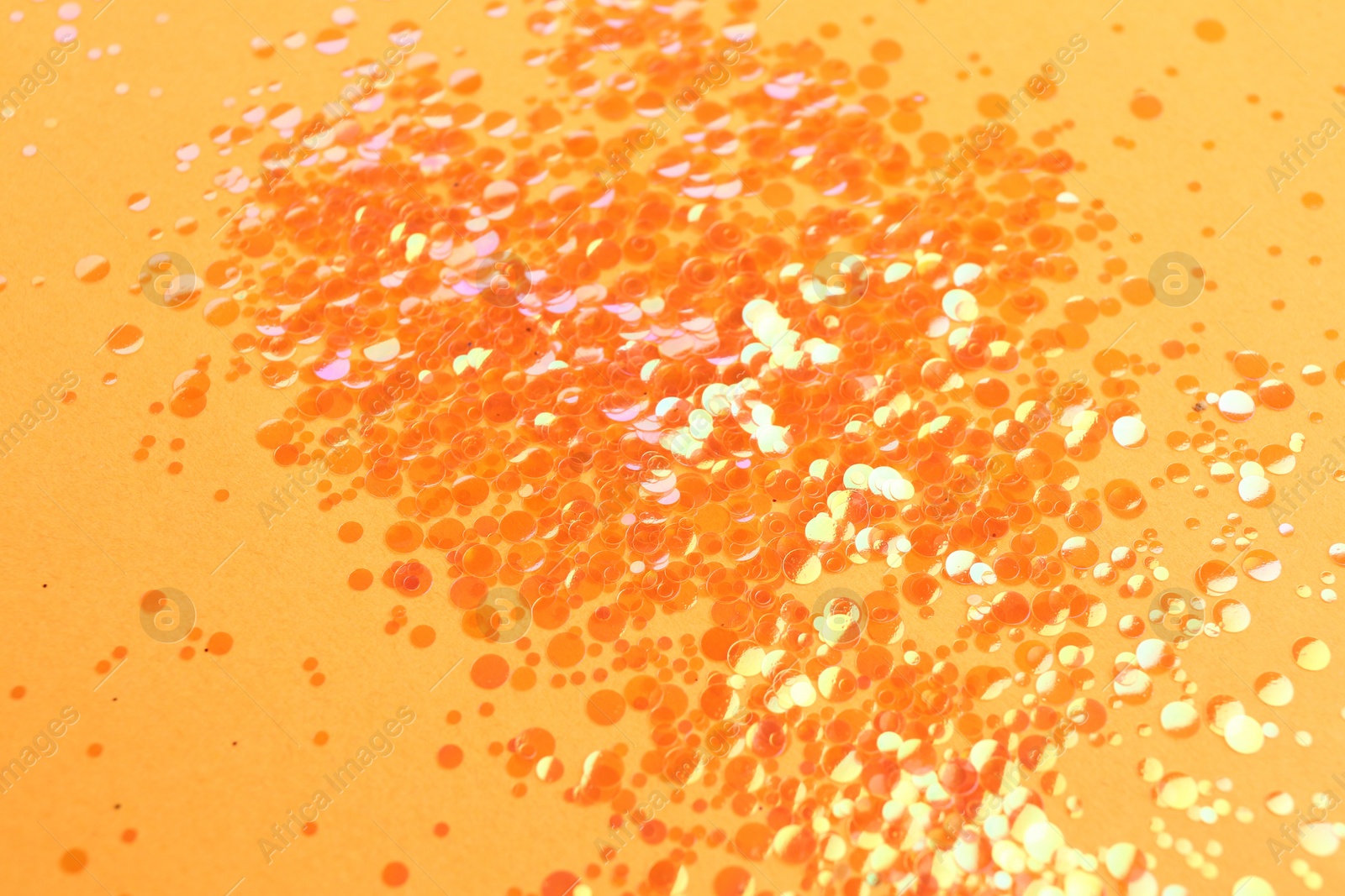 Photo of Pile of shiny bright glitter on orange background