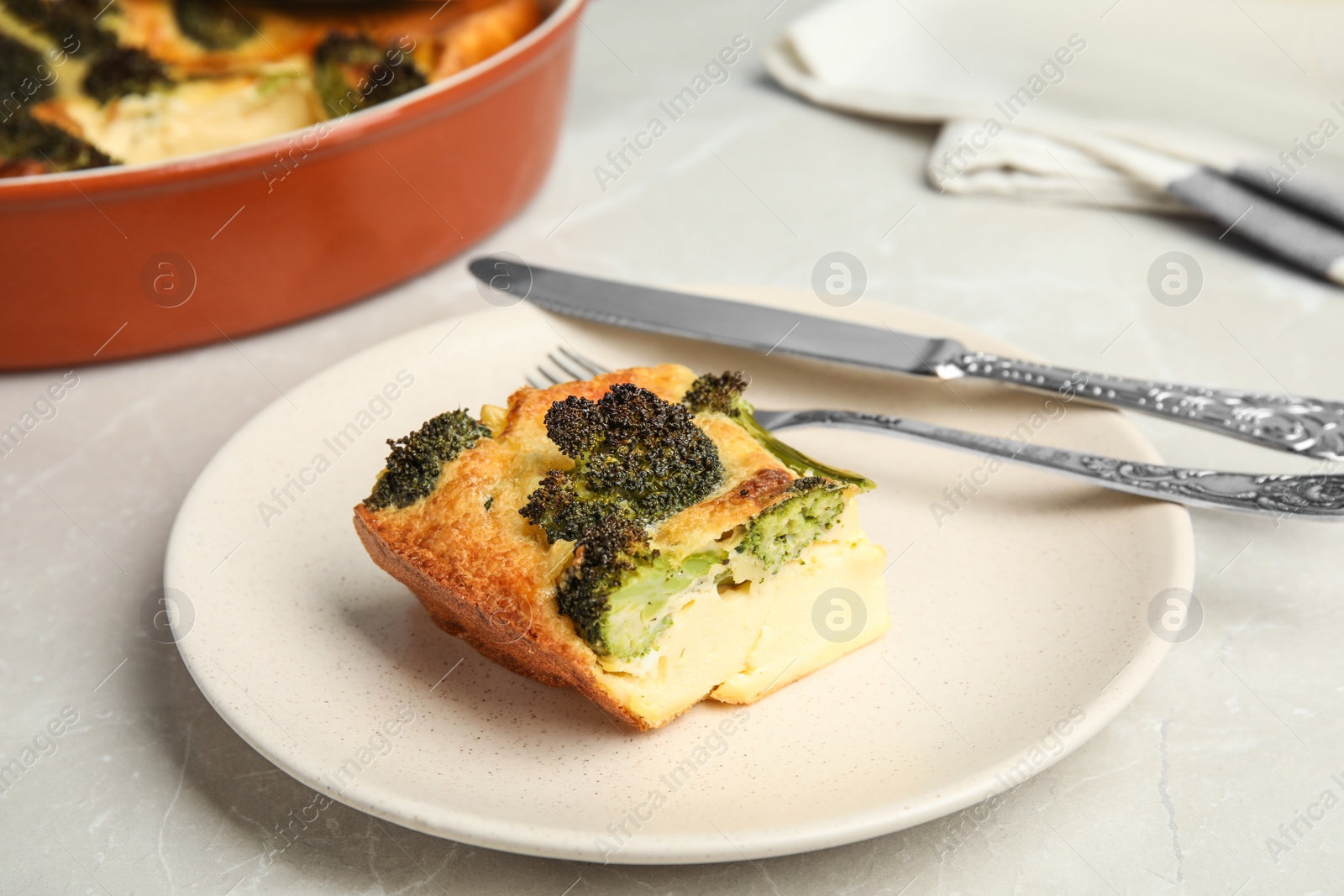 Photo of Tasty broccoli casserole served on grey marble table