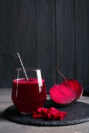 Slate plate with glass of beet smoothie on table, space for text