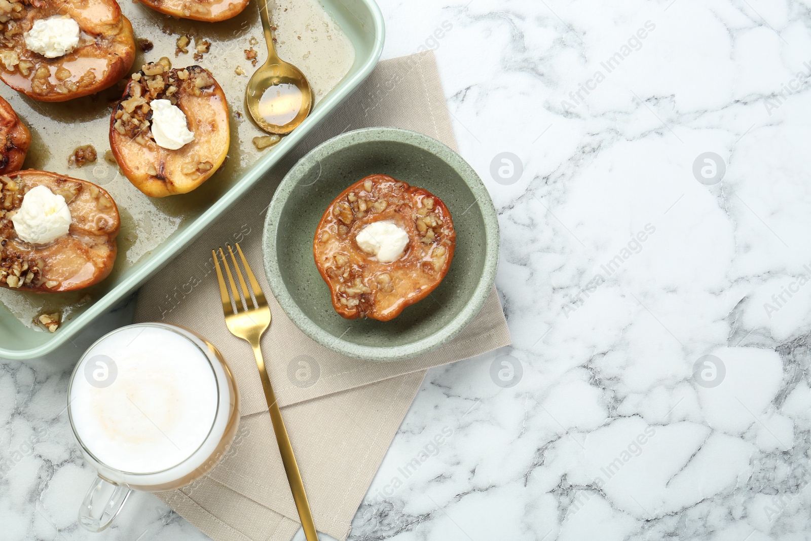Photo of Tasty baked quinces with nuts and cream cheese served on white marble table, flat lay. Space for text