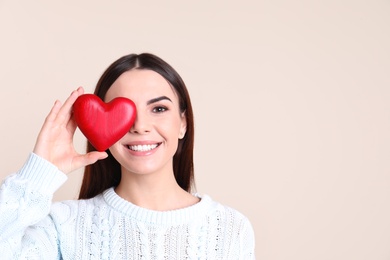 Photo of Portrait of young woman with decorative red heart on color background, space for text