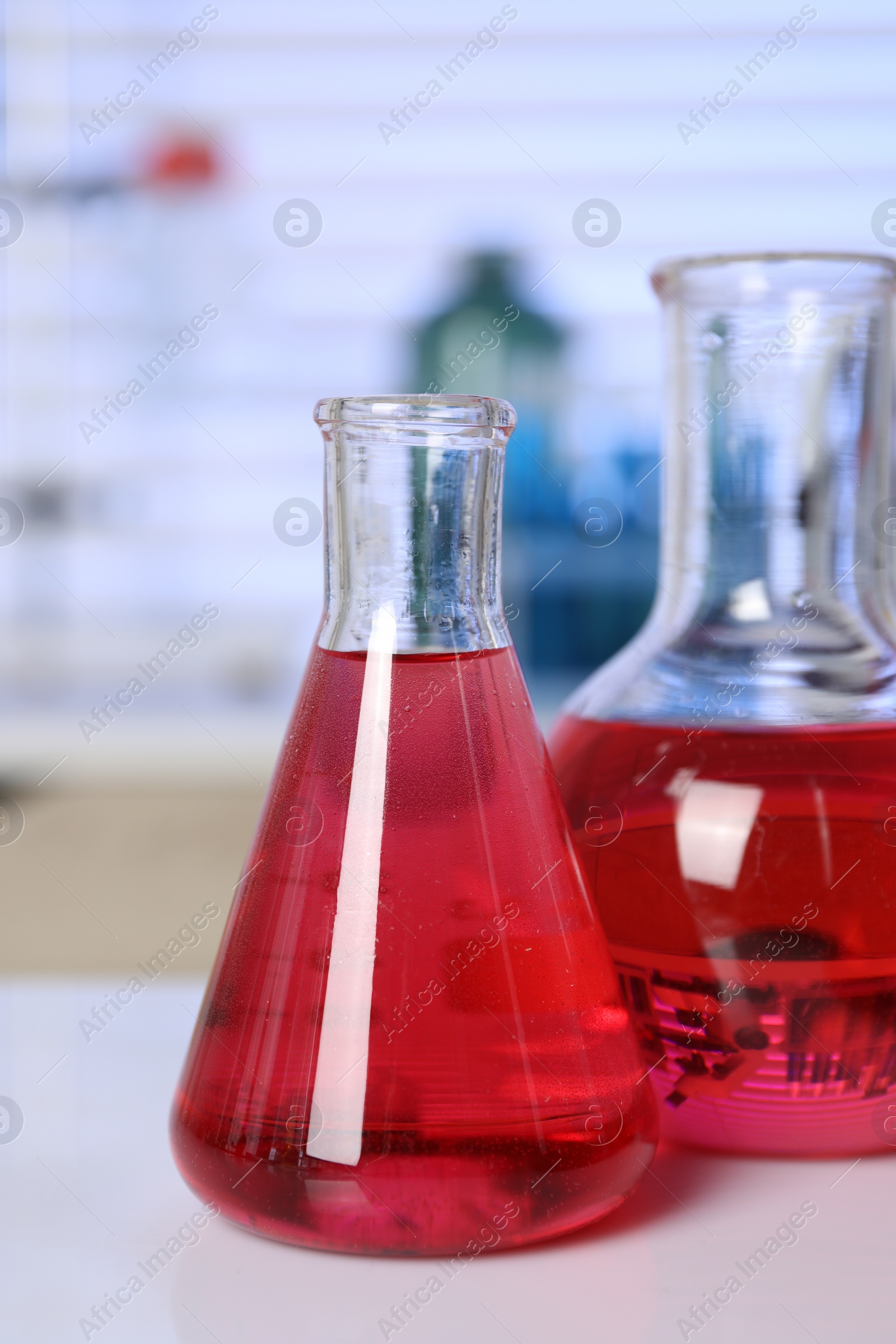 Photo of Laboratory analysis. Different glassware with red liquid on white table indoors