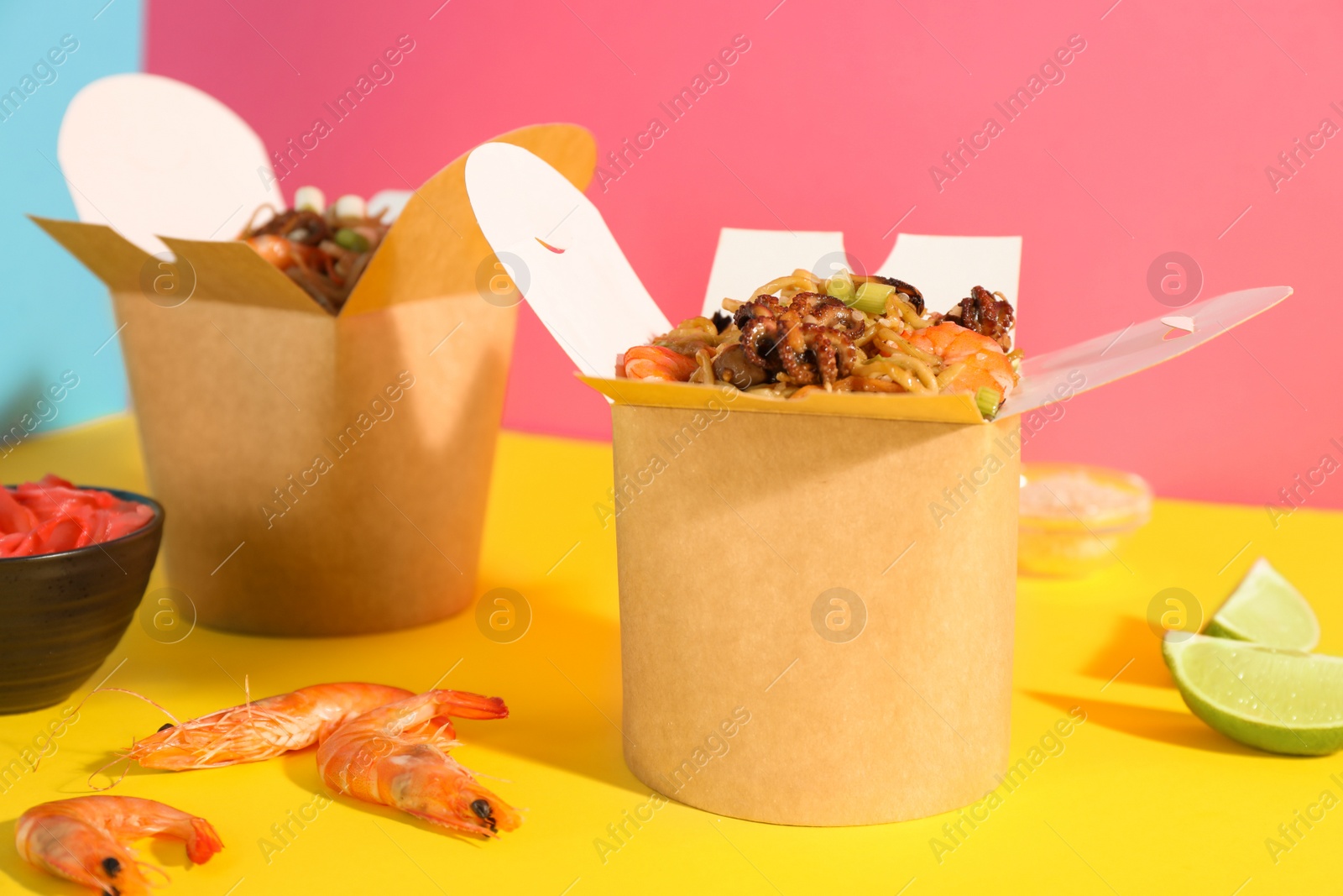 Photo of Boxes of wok noodles with seafood on color background, closeup