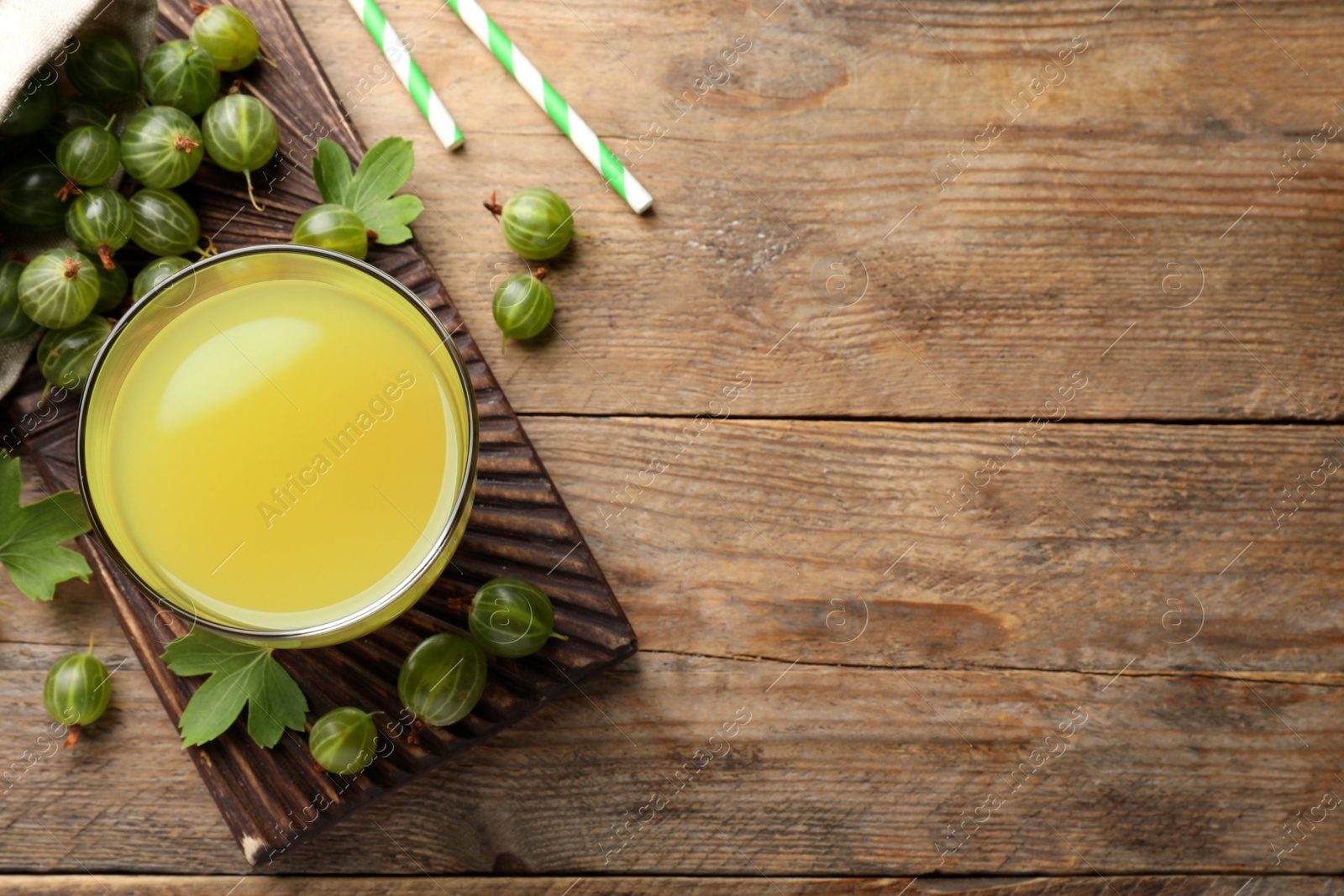 Photo of Tasty gooseberry juice and fresh berries on wooden table, flat lay. Space for text