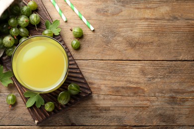 Photo of Tasty gooseberry juice and fresh berries on wooden table, flat lay. Space for text