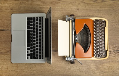 Old typewriter and laptop on wooden table, flat lay. Concept of technology progress