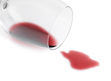 Photo of Transparent glass and spilled exquisite red wine on white background