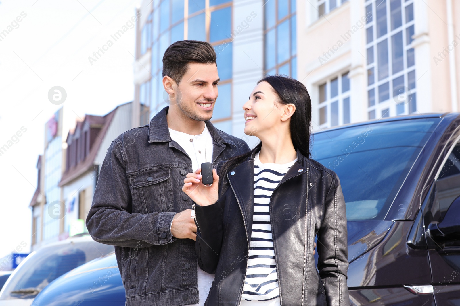 Photo of Happy couple with key near car on city street. Buying new auto