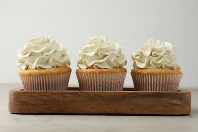 Photo of Tasty cupcakes with vanilla cream on light grey table, closeup