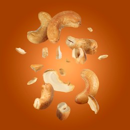 Image of Tasty cashew nuts flying on orange background