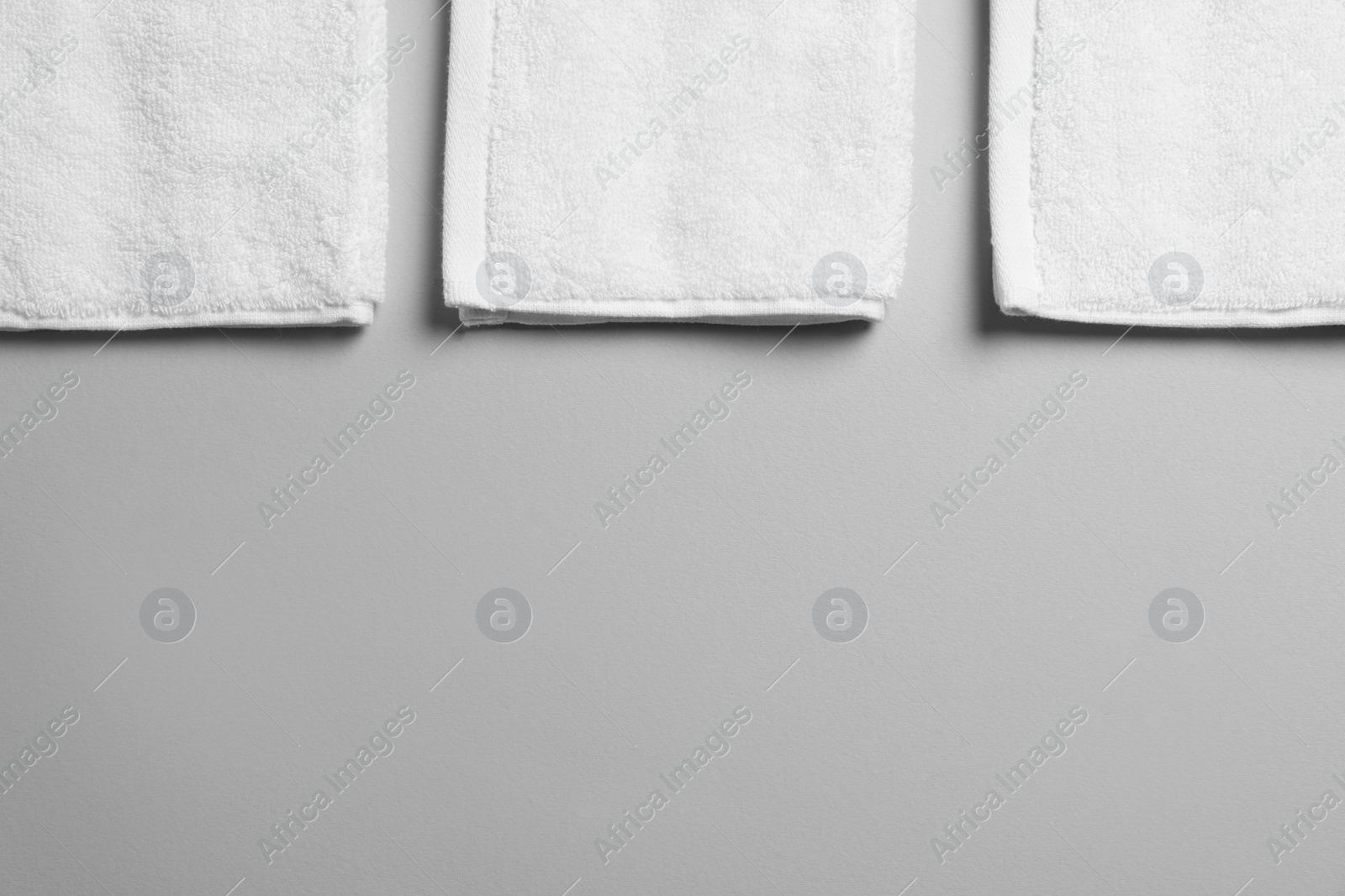 Photo of Soft folded white towels on light grey background, flat lay