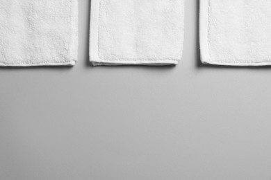 Soft folded white towels on light grey background, flat lay