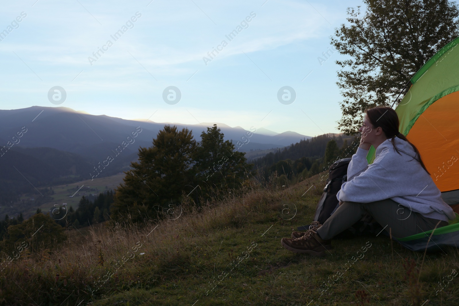 Photo of Tourist with camping tent sitting on hill in mountains