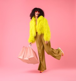 Photo of Happy young woman with shopping bags on pink background. Space for text