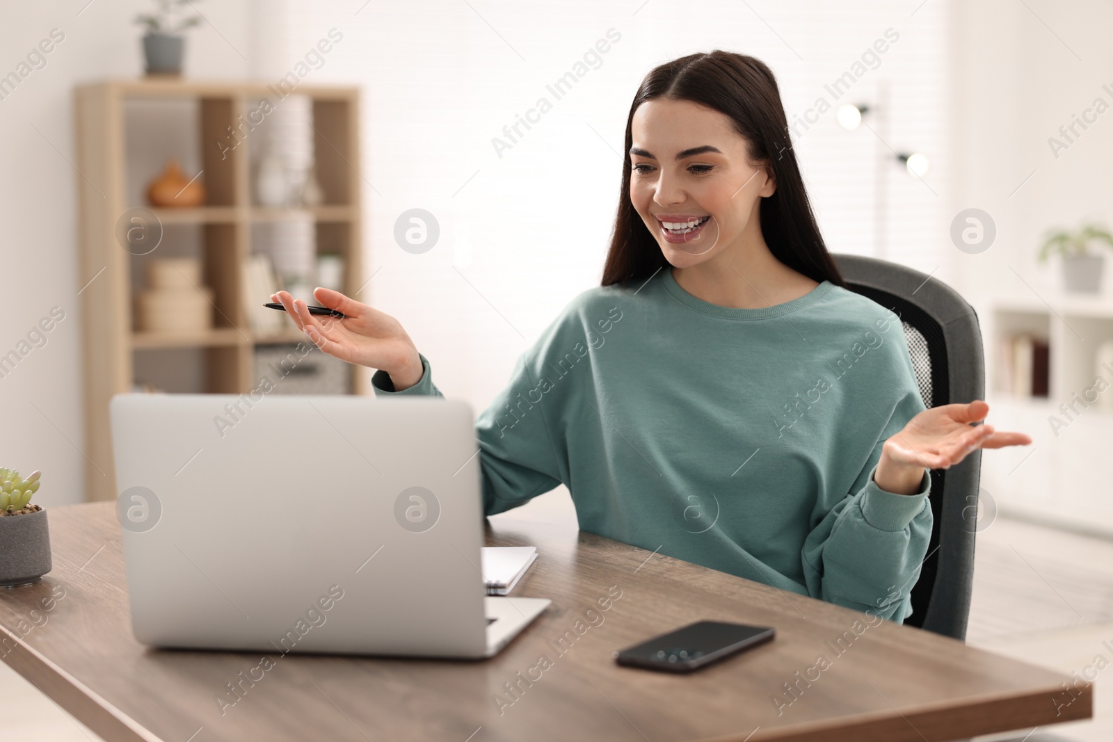 Photo of Young woman using video chat during webinar at table in room