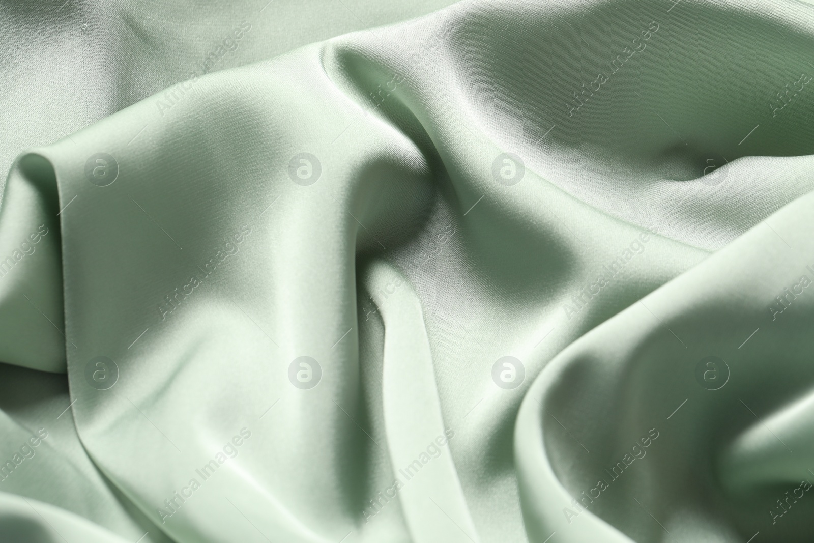 Photo of Texture of light green crumpled silk fabric as background, top view