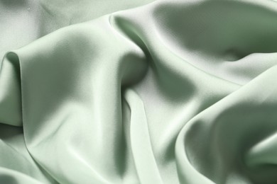 Texture of light green crumpled silk fabric as background, top view