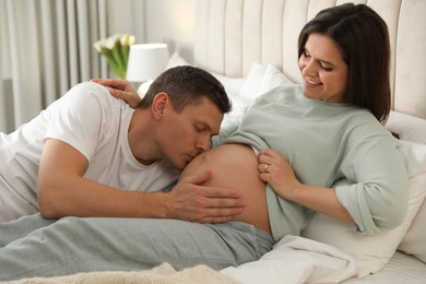 Photo of Young pregnant woman with her husband in bedroom