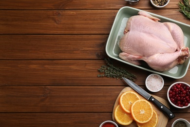 Photo of Flat lay composition with raw chicken and orange slices on wooden table. Space for text