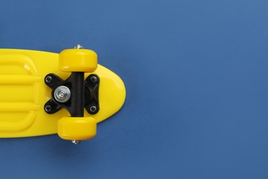 Photo of Yellow skateboard on blue background, top view. Space for text