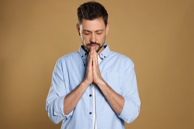 Man with clasped hands praying on beige background