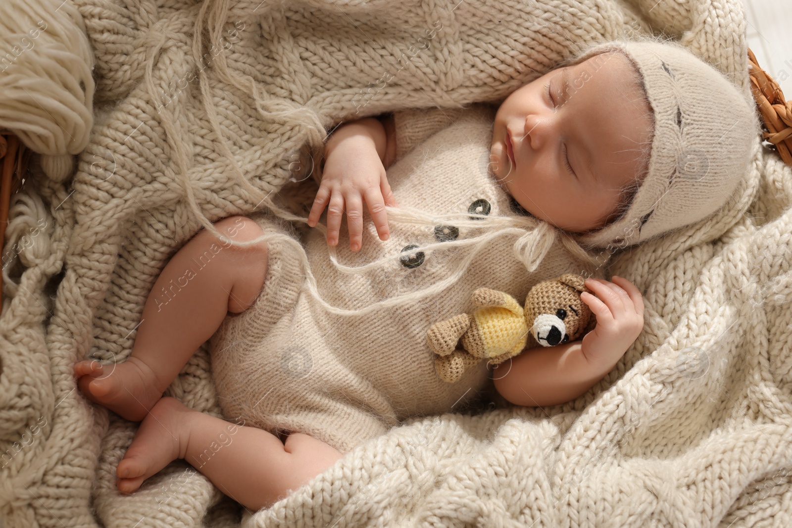 Photo of Adorable newborn baby with toy bear sleeping in wicker basket, top view