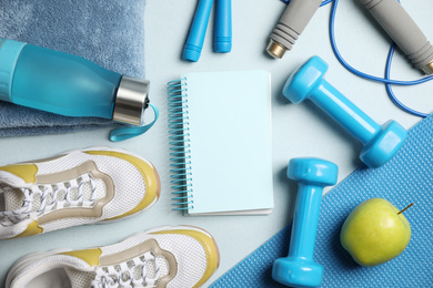 Photo of Flat lay composition with fitness equipment and notebook on light blue background, space for text