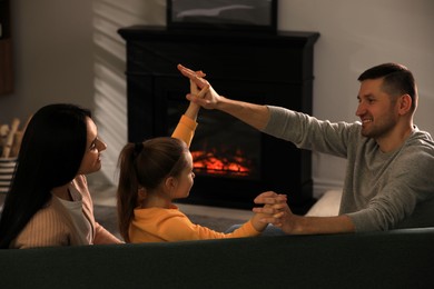 Happy family spending time together on sofa near fireplace at home