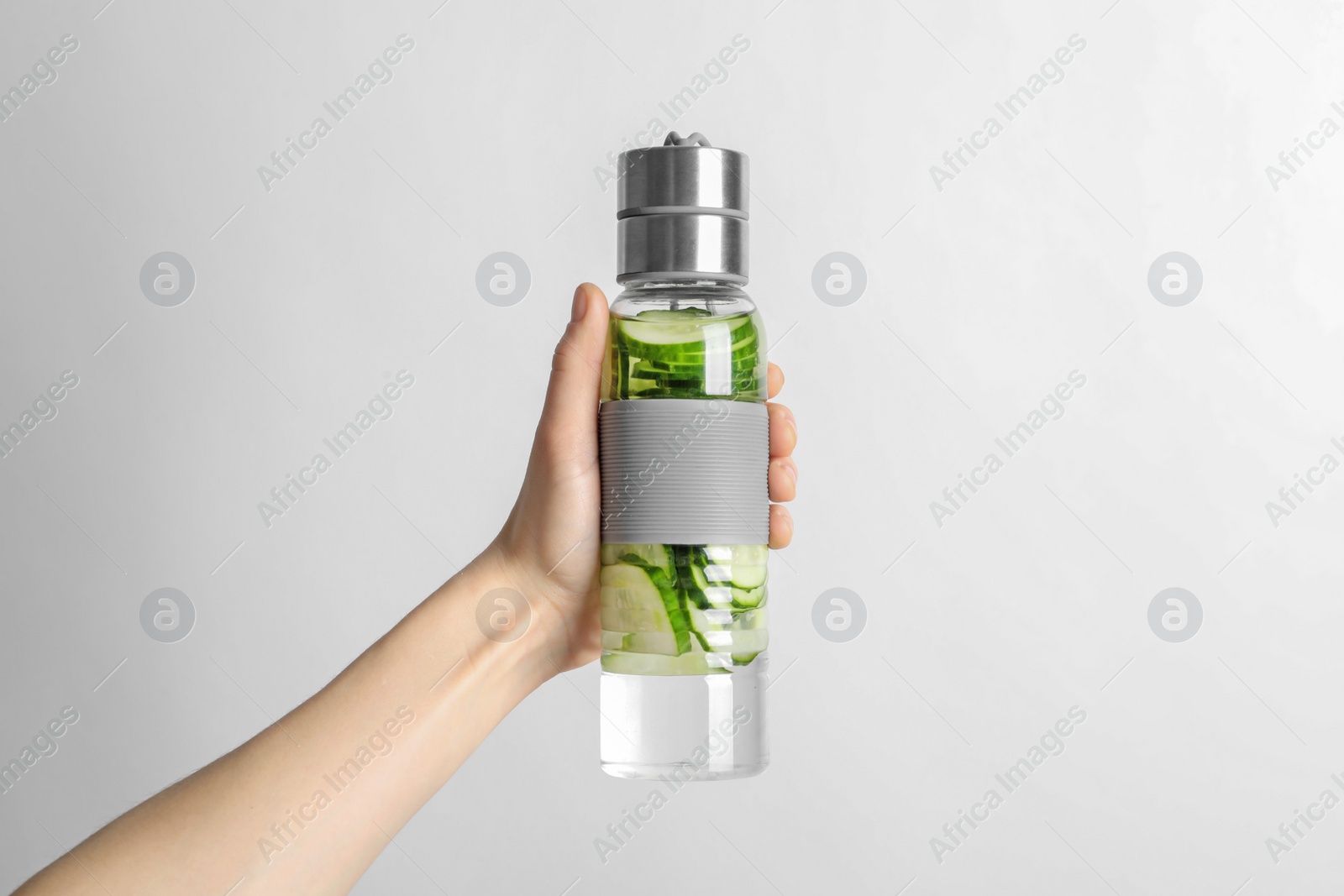 Photo of Young woman holding bottle with fresh cucumber water on white background. Space for text