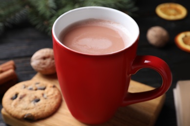 Photo of Cup of tasty cocoa and cookie on wooden board