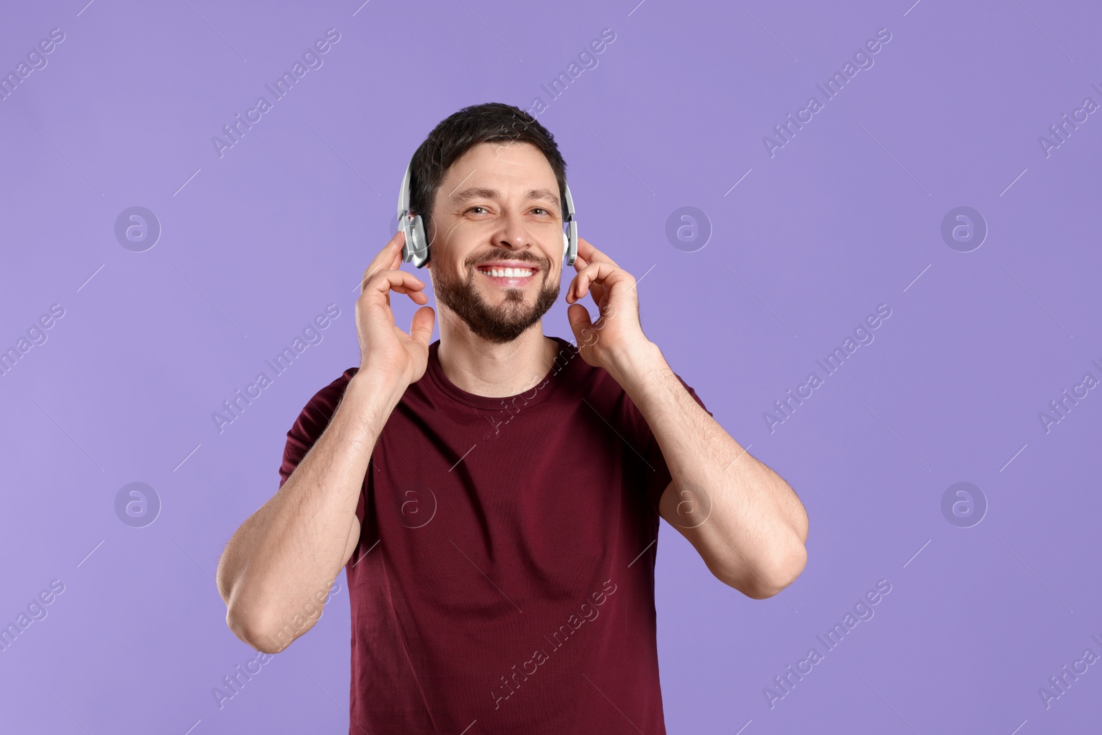 Photo of Happy man in headphones enjoying music on purple background