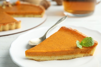 Piece of delicious fresh homemade pumpkin pie on white wooden table, closeup