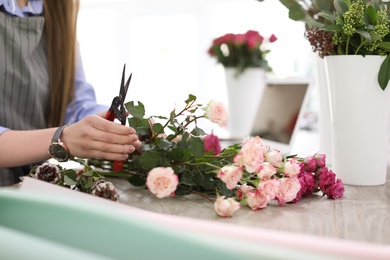 Photo of Female florist making beautiful bouquet in flower shop, closeup