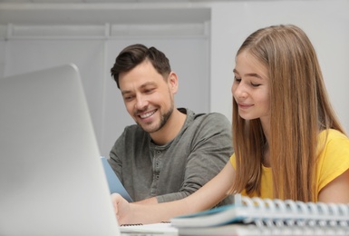 Father helping his teenager daughter with homework indoors