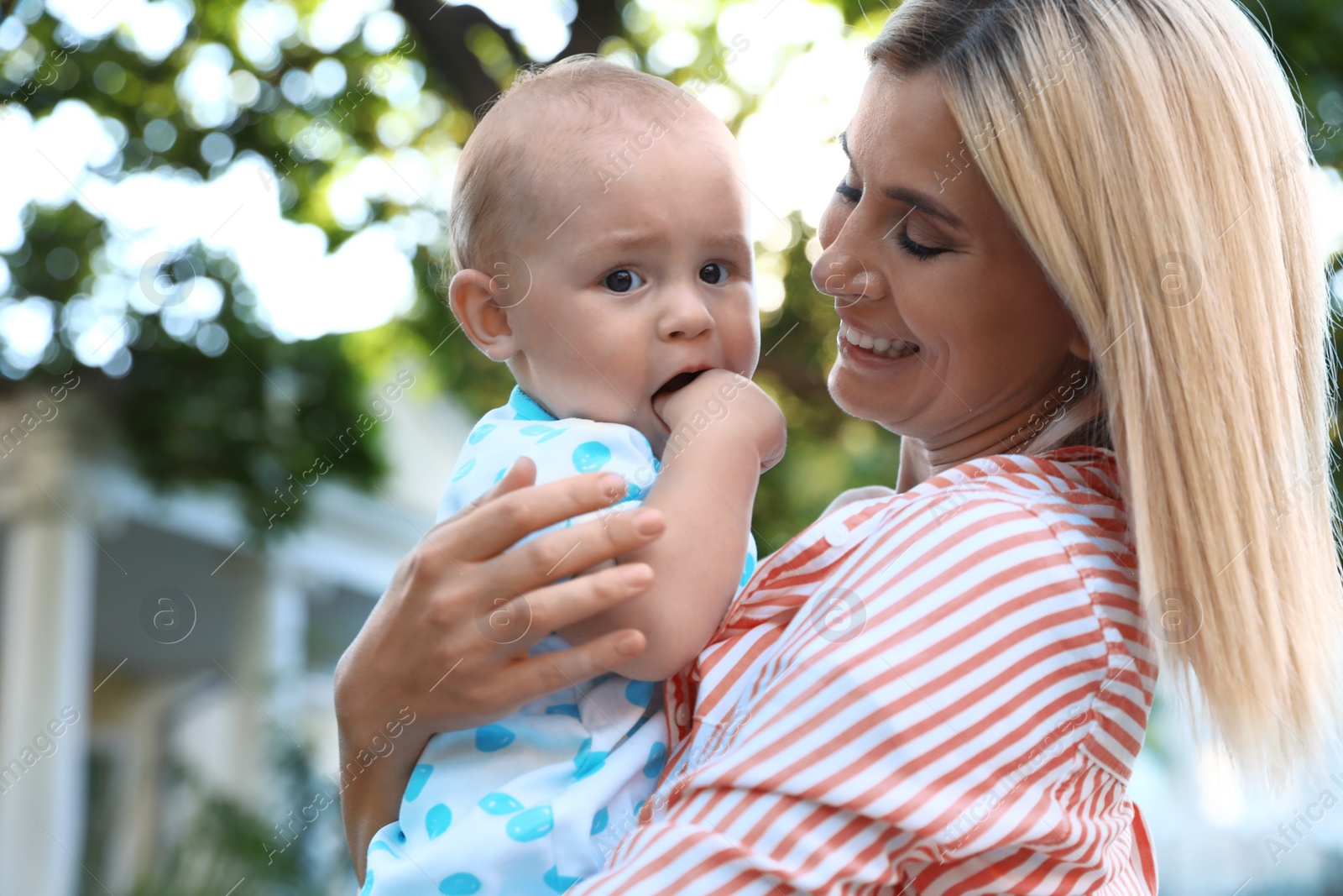 Photo of Nanny with cute baby outdoors on sunny day