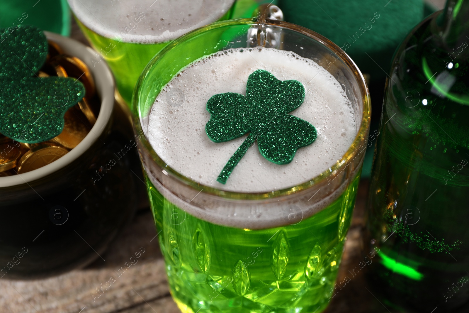 Photo of St. Patrick's day party. Green beer, leprechaun pot of gold and decorative clover leaves on wooden table, closeup