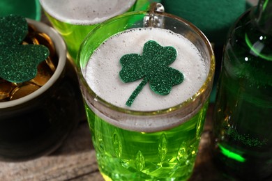 Photo of St. Patrick's day party. Green beer, leprechaun pot of gold and decorative clover leaves on wooden table, closeup