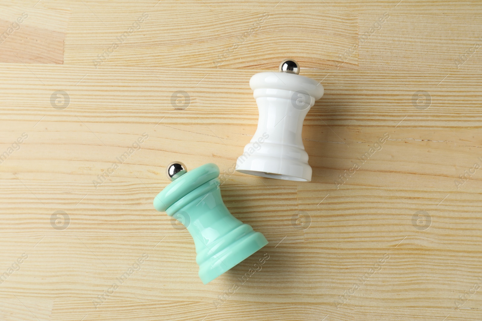 Photo of Salt and pepper shakers on light wooden table, top view