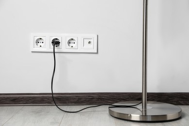 Photo of Floor lamp plugged into wall power socket indoors