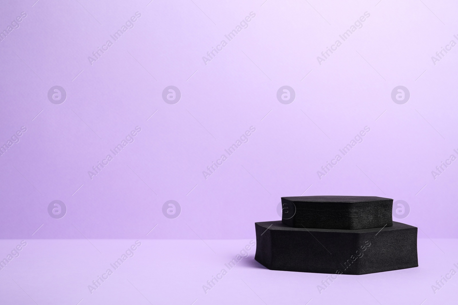 Photo of Black geometric figures on violet background, space for text. Stylish presentation for product