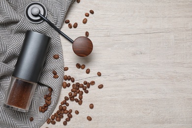 Photo of Flat lay composition with coffee grinder and beans on white wooden table. Space for text